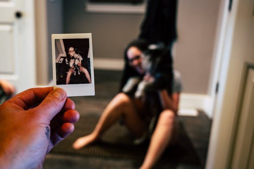 显示宝丽来照片的女人抱着狗的人 · 免费素材图片