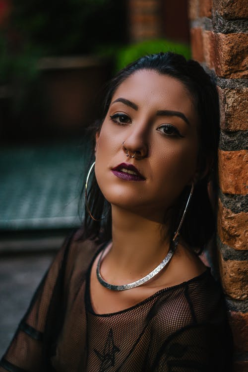 穿黑纯粹的女人，靠在棕色砖墙上 · 免费素材图片