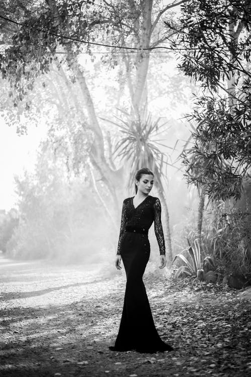 女人站在高大的树木附近的灰度摄影 · 免费素材图片