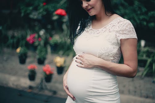 孕妇在抱着她的肚子的白色连衣裙的特写照片 · 免费素材图片