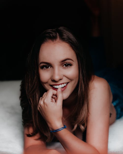 用左手指在嘴唇上微笑的女人 · 免费素材图片