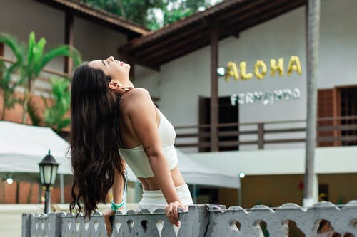 在木制的篱笆上向后倾斜的白色服装的女人的照片 · 免费素材图片