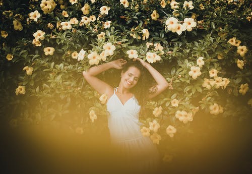 女人穿着白色的衣服，躺在黄色的花朵上 · 免费素材图片