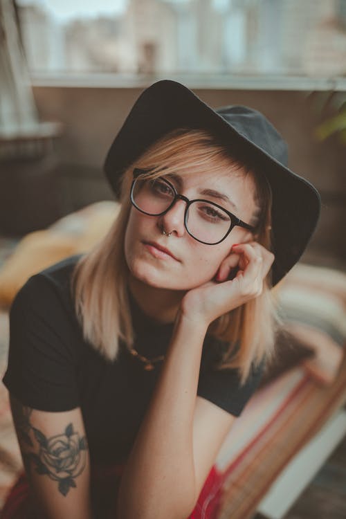黑色的帽子和t恤，她的头靠在她的左手的女人的特写照片 · 免费素材图片