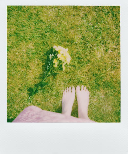 站在花瓣花旁边的草地上的人 · 免费素材图片