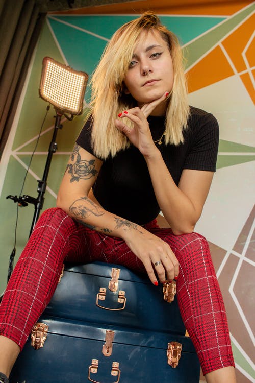 女人抱着她的下巴坐在蓝色的手提箱上的照片 · 免费素材图片