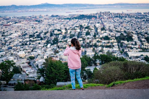 穿粉色连帽衫拍照的城市女孩 · 免费素材图片
