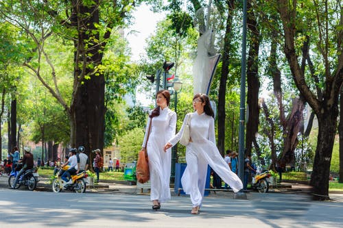 穿白色衣服的两个女人在过马路时手牵着手的照片 · 免费素材图片