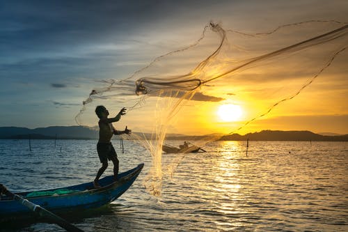 人站在船上扔鱼网 · 免费素材图片