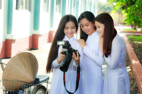 白色服装的三名妇女的照片，检查单反相机屏幕上的照片。 · 免费素材图片