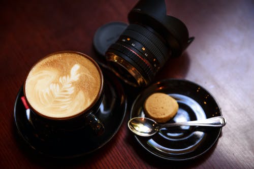 黑茶杯充满咖啡在相机镜头旁边 · 免费素材图片