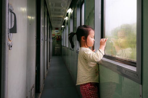 在火车走廊里看着外面的女孩支持窗口的照片同时拍照 · 免费素材图片