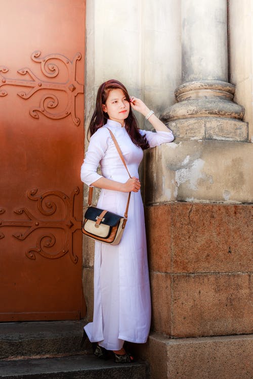 站在棕色门前的白色服装的女人的照片 · 免费素材图片