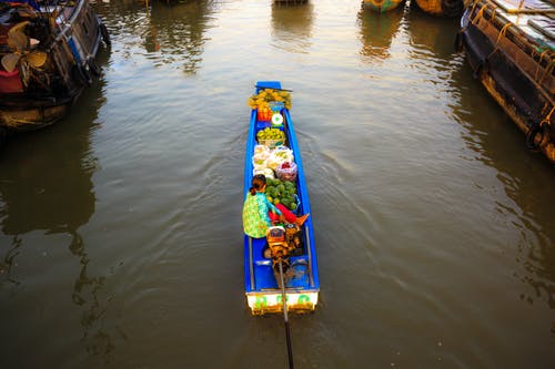 女人在河船充满水果和蔬菜 · 免费素材图片