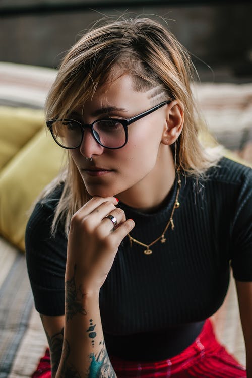 黑色上衣的女人，她的下巴坐在床上的右手腕上的下巴 · 免费素材图片