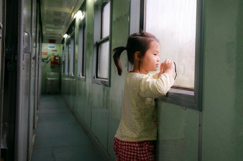 在火车走廊里望着外面的女孩支持窗口的照片 · 免费素材图片