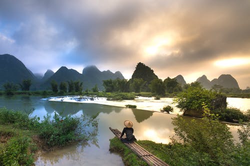 坐在竹子附近的水体上的人 · 免费素材图片