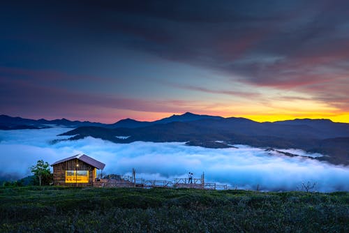 棕色木制小屋，可欣赏云层和山 · 免费素材图片