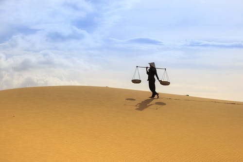 女人在沙漠上进行轭时按住轭 · 免费素材图片