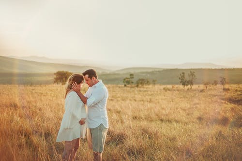 男人和女人面对面站在棕色的草田 · 免费素材图片