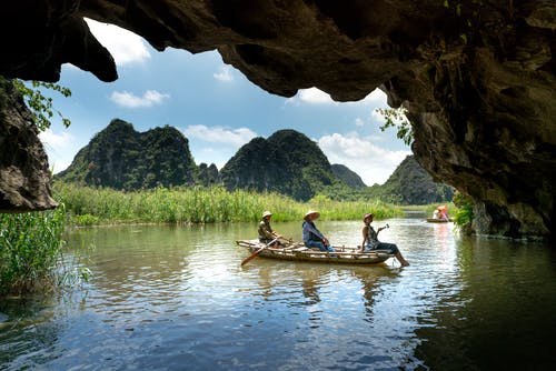 三人坐在洞穴下航行时的船上 · 免费素材图片