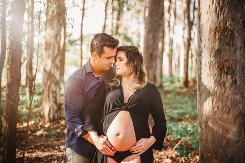 怀孕的女人和男人站在森林里 · 免费素材图片