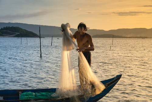 男子在船上起重鱼网 · 免费素材图片