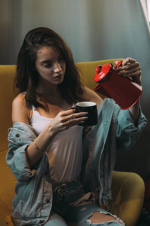 女人穿着白色背心倒在杯子上的咖啡 · 免费素材图片