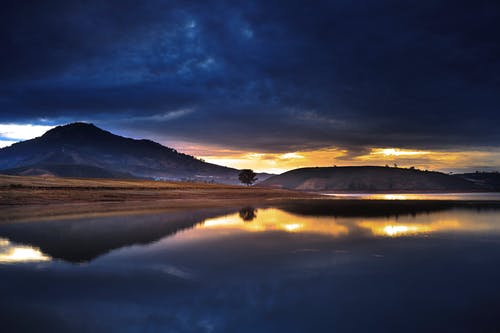 黎明时分穿过平静的河水所见的山景 · 免费素材图片