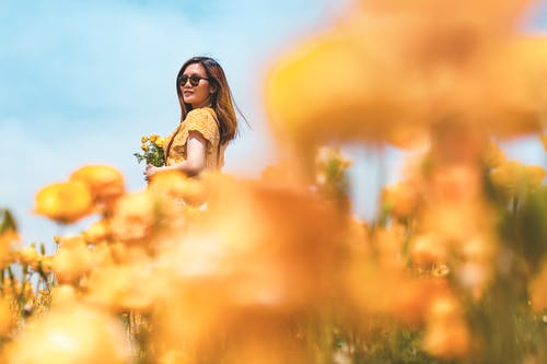 站立时拿着黄色花的女人 · 免费素材图片