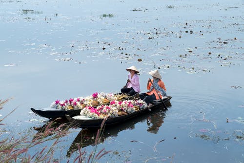 两名女子骑着独木舟与花的照片 · 免费素材图片