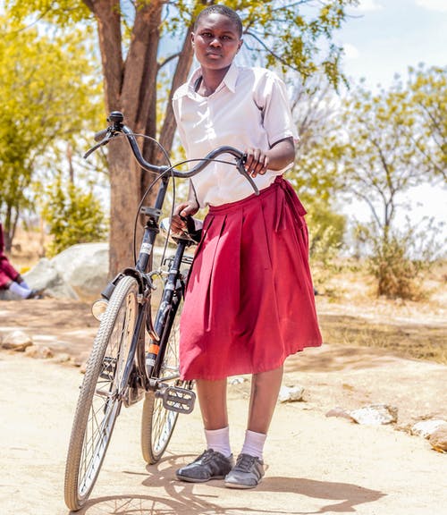 女人抱着黑色的自行车，附近绿叶树 · 免费素材图片