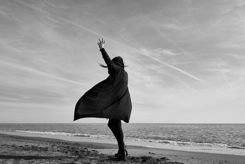 女人站在海边的灰度摄影 · 免费素材图片