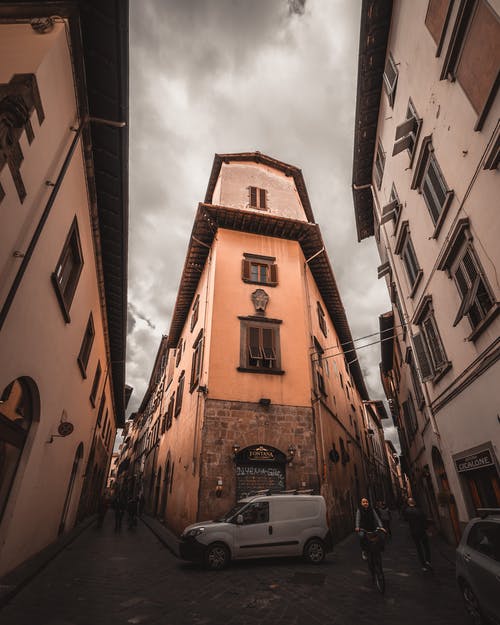 白色车辆停在街上行走的人附近的建筑物旁边 · 免费素材图片