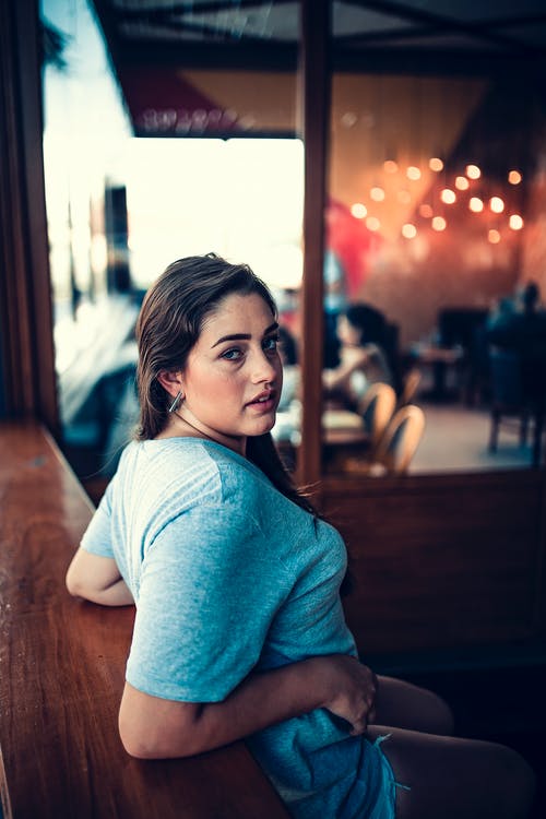 靠在一张木桌上的女人的照片 · 免费素材图片