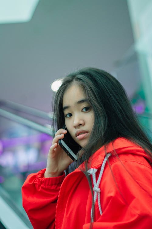 女孩穿着红色夹克谈手机的特写照片 · 免费素材图片