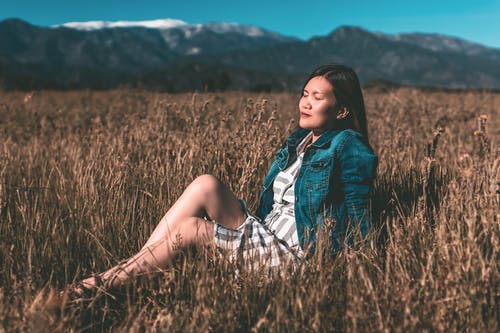 女人坐在棕色的干草田 · 免费素材图片