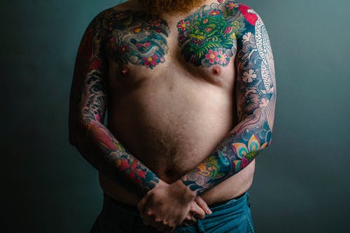 彩色的花卉袖纹身覆盖人的手臂和胸部 · 免费素材图片