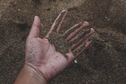 拿着沙子的人的特写照片 · 免费素材图片