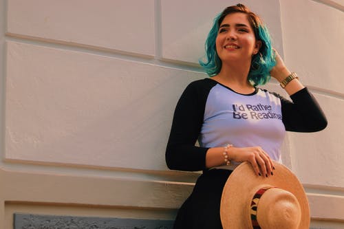 白色和黑色的插肩式3/4袖t恤站在白墙上的微笑妇女的特写照片 · 免费素材图片