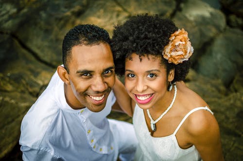 一个男人和一个女人站在岩石上微笑的照片 · 免费素材图片