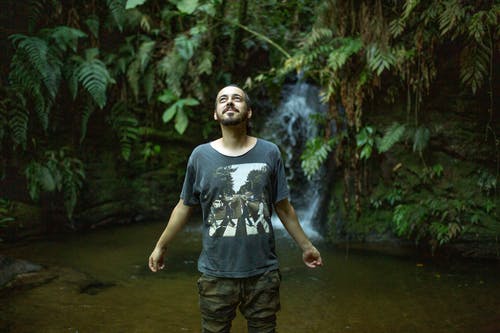 身穿黑色圆领t恤和棕色底裤站在水流附近的人 · 免费素材图片