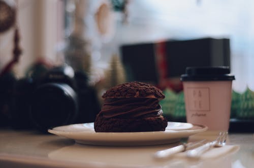 咖啡杯和单反相机旁边的巧克力甜点板 · 免费素材图片
