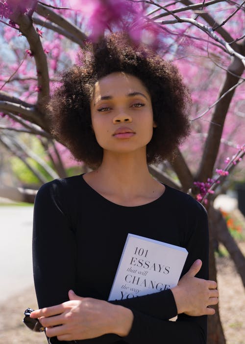 站在树旁拿着本书的女人 · 免费素材图片