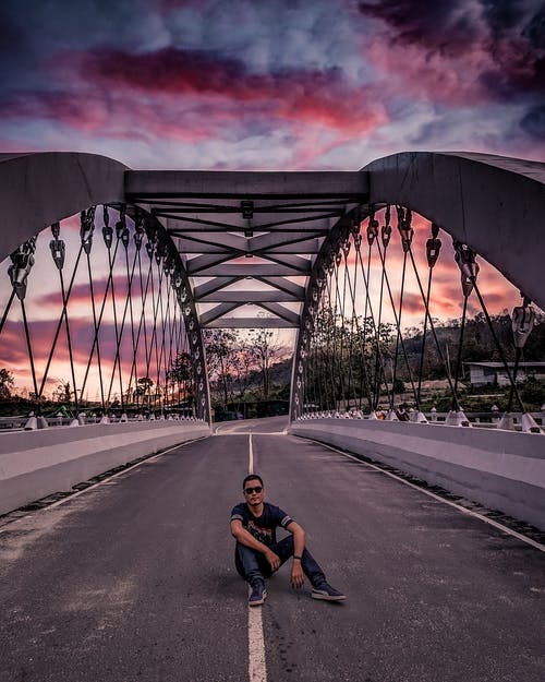 男子坐在桥中间 · 免费素材图片