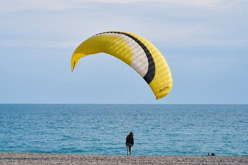 黄色和白色滑翔伞在海边的人 · 免费素材图片