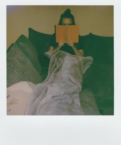 女人坐在沙发上看书 · 免费素材图片