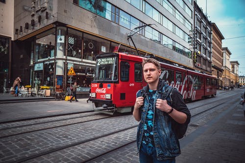 男子站在红色电车附近 · 免费素材图片