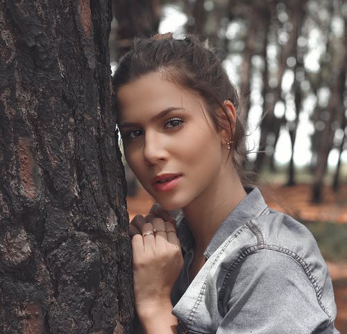 倚在树上的蓝色牛仔外套的女人 · 免费素材图片