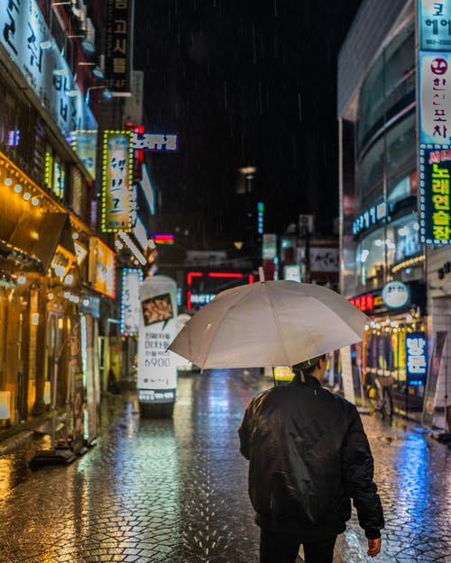 男人穿着黑夹克拿着雨伞 · 免费素材图片